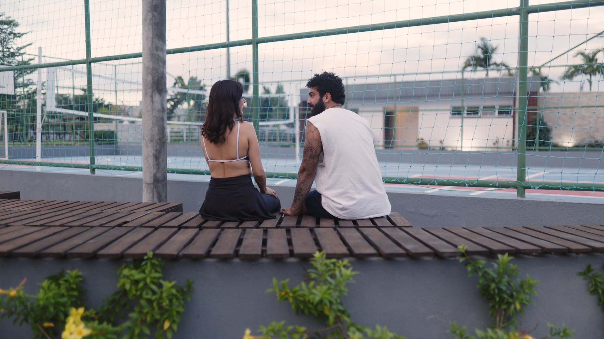 Casal sentado no deck em frente à quadra
